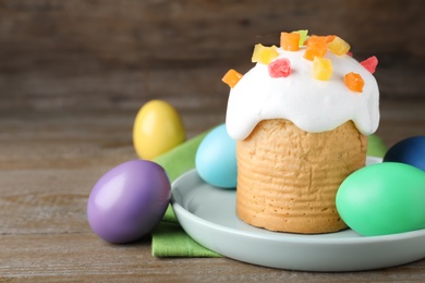 Photo of Traditional decorated Easter cake and colorful eggs on wooden table, closeup. Space for text