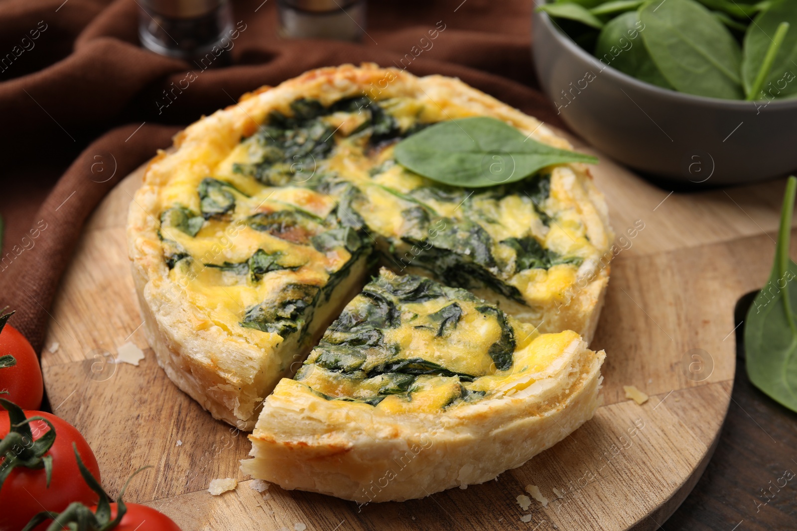 Photo of Delicious pie with spinach on wooden table, closeup