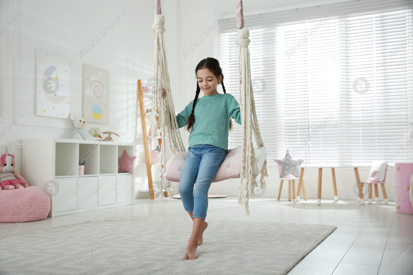 Photo of Cute little girl playing on swing at home