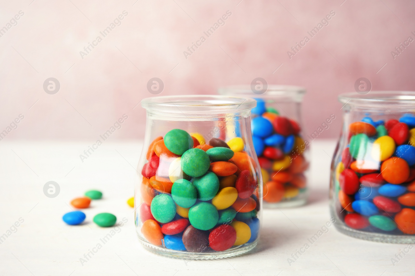 Photo of Jars with small colorful candies on table