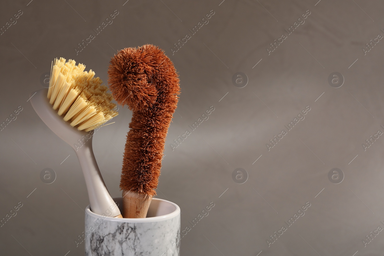 Photo of Cleaning brushes in holder on grey background, closeup. Space for text