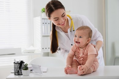 Photo of Young pediatrician examining cute little baby in clinic