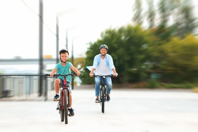 Image of Dad and son riding bicycles together outdoors, motion blur effect
