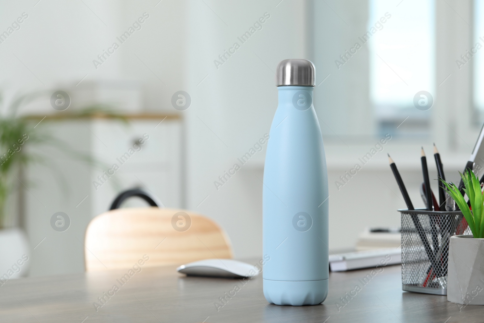 Photo of Stylish thermo bottle on wooden table at home. Space for text