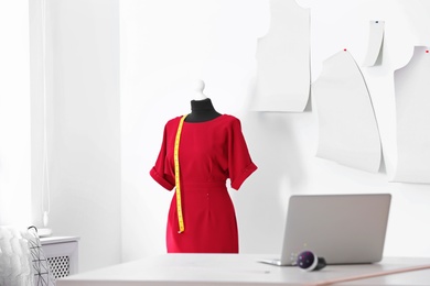 Photo of Mannequin with dress and measuring tape in tailor studio