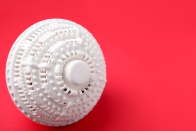 Photo of Laundry dryer ball on red background, space for text