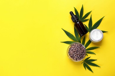 Flat lay composition with CBD oil or THC tincture and hemp leaves on yellow background, space for text