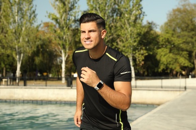 Photo of Man wearing modern smart watch during training near river