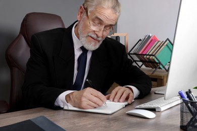 Senior boss working at wooden table in office