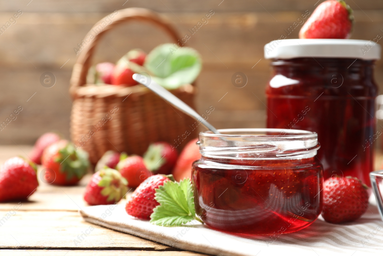 Photo of Delicious pickled strawberry jam and fresh berries on wooden table