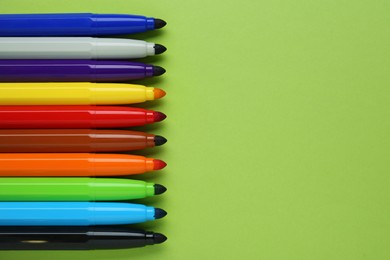 Photo of Many different colorful markers on light green background, flat lay. Space for text