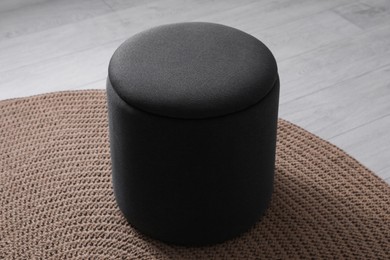 Photo of Stylish black ottoman on floor in room