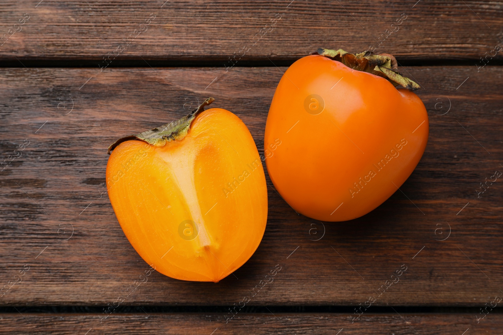 Photo of Delicious ripe persimmons on wooden table, flat lay