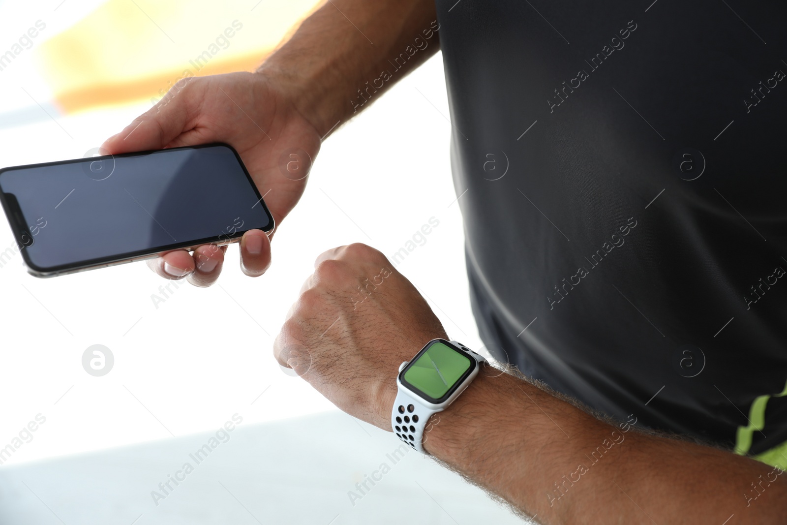 Photo of Man with smartphone checking fitness tracker in gym, closeup