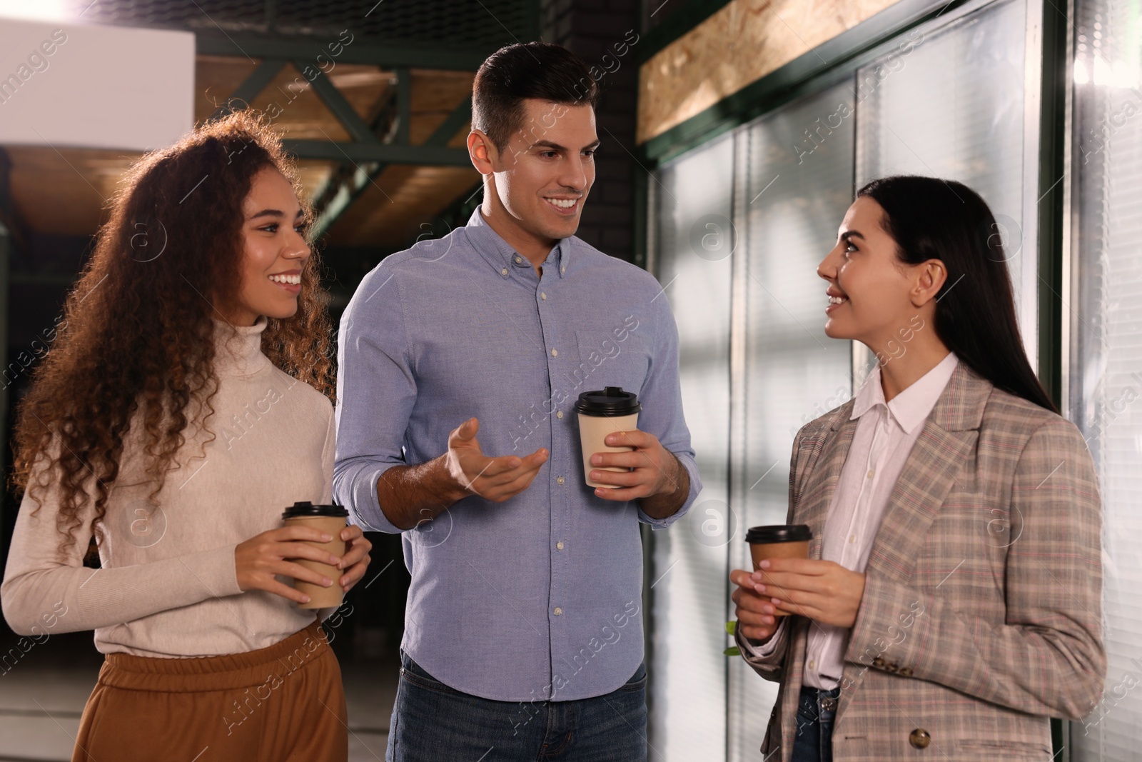 Photo of Group of coworkers talking during coffee break in office