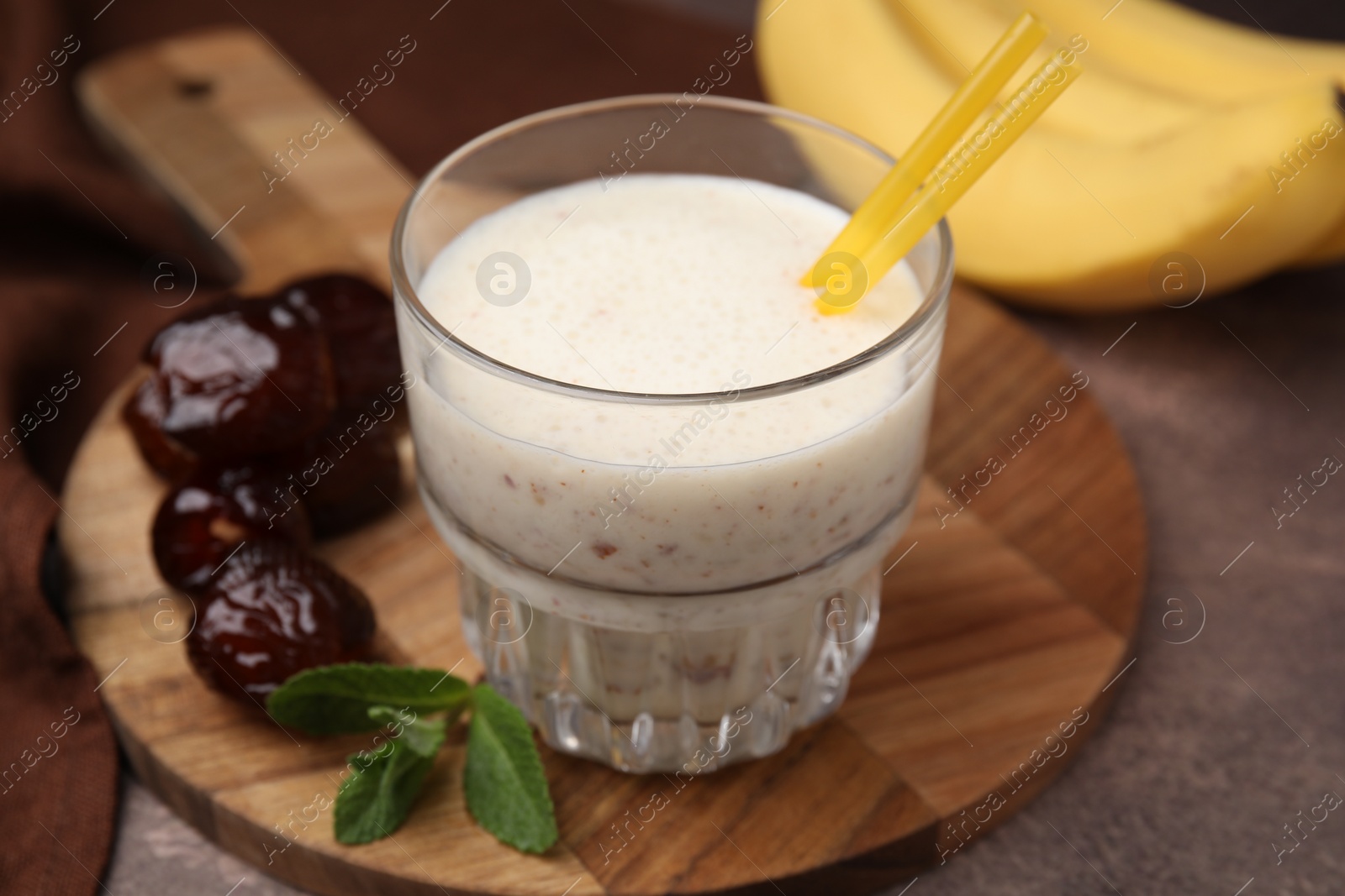 Photo of Glass of delicious date smoothie, mint and dried fruits on brown table, closeup