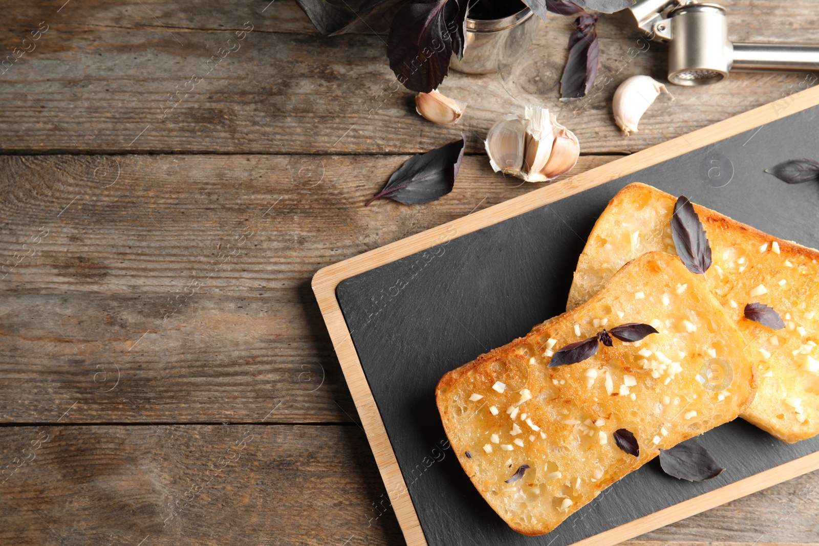 Photo of Flat lay composition with tasty garlic and space for text bread on table