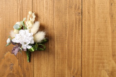 Photo of Stylish boutonniere on wooden table, top view. Space for text