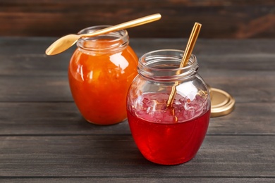 Jars with tasty sweet jam on wooden table