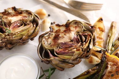 Photo of Tasty grilled artichoke served on table, closeup