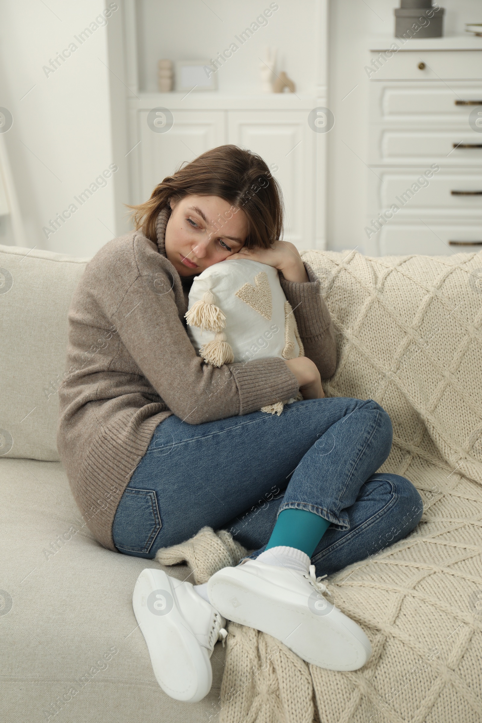 Photo of Sad young woman sitting on sofa at home