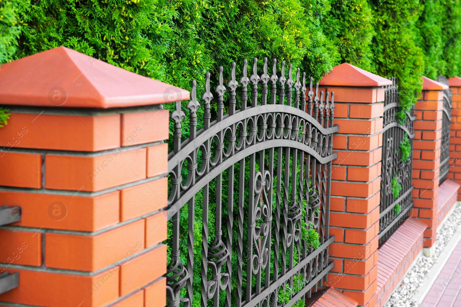 Photo of Beautiful brick fence with iron railing outdoors