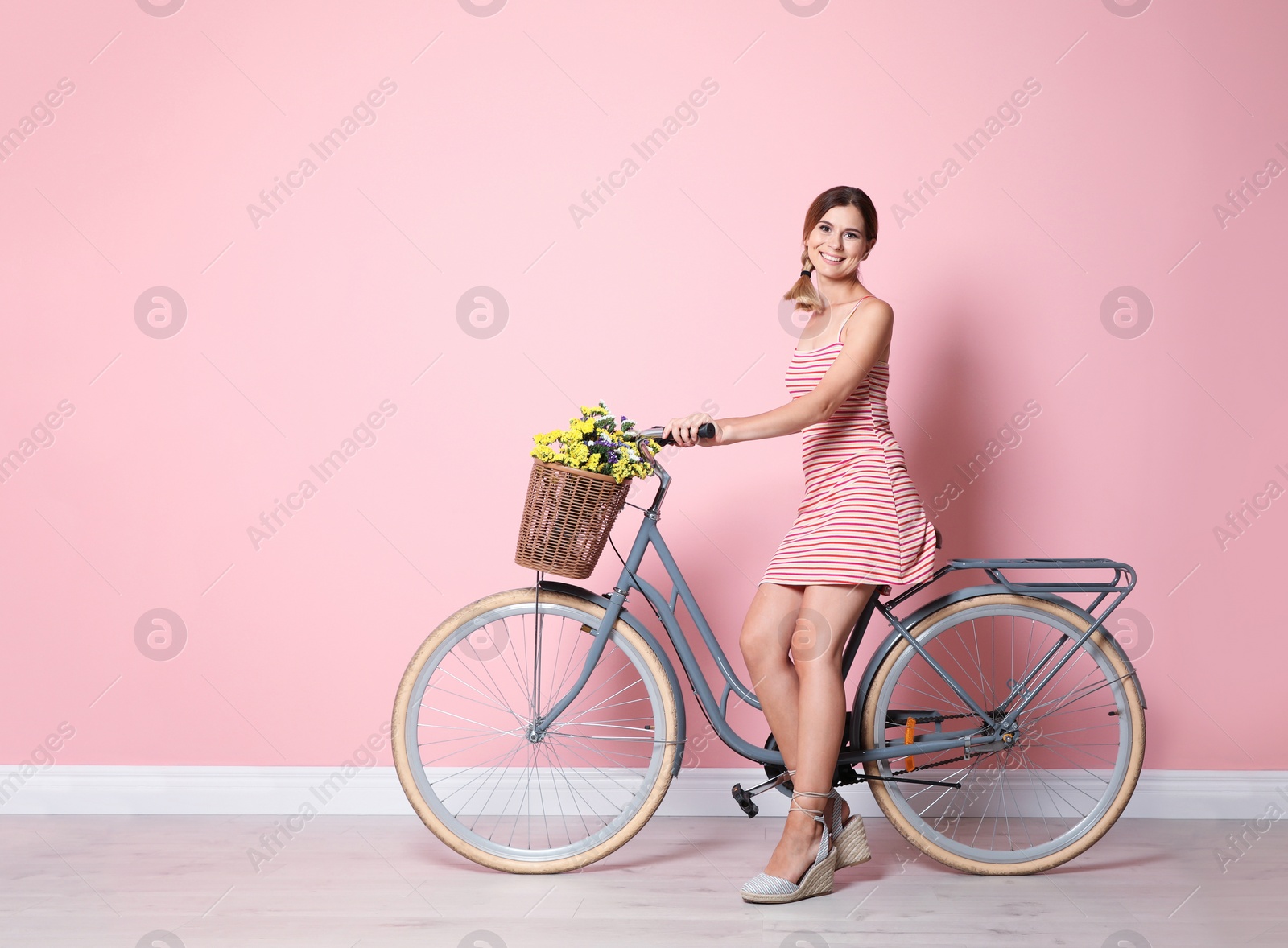 Photo of Portrait of beautiful woman with bicycle near color wall