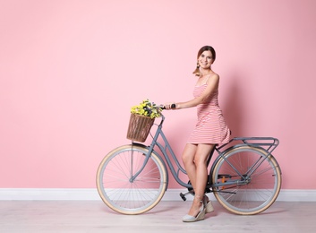 Photo of Portrait of beautiful woman with bicycle near color wall