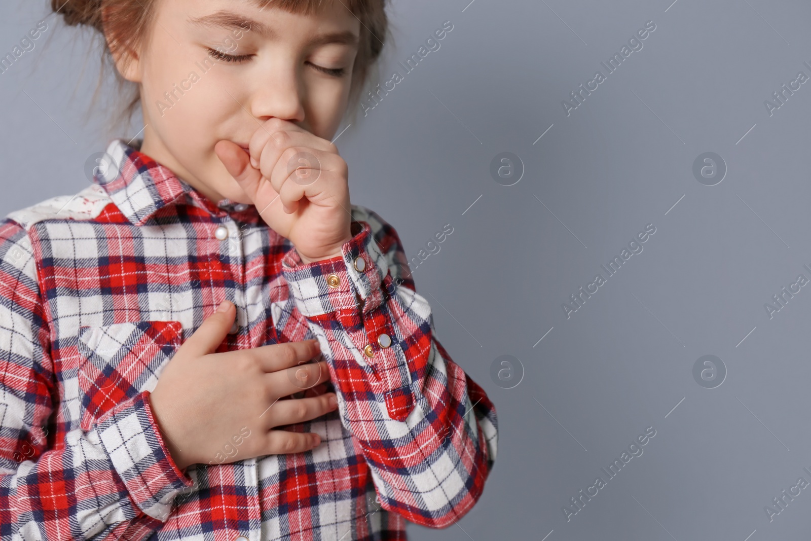 Photo of Little girl coughing on grey background