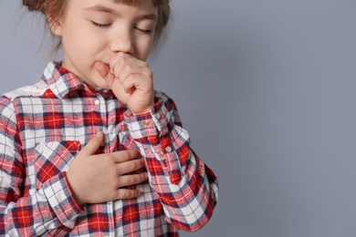 Little girl coughing on grey background
