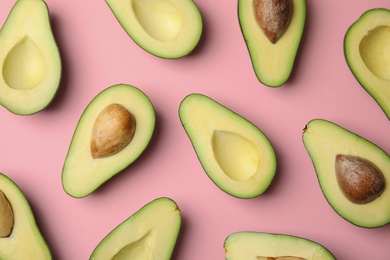 Cut fresh ripe avocados on pink background, flat lay