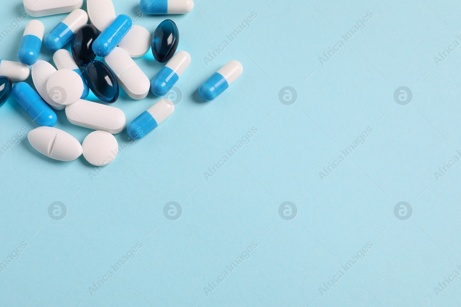 Photo of Many different pills on light blue background, space for text