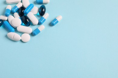 Many different pills on light blue background, space for text