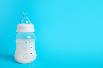 One feeding bottle with milk on light blue background. Space for text