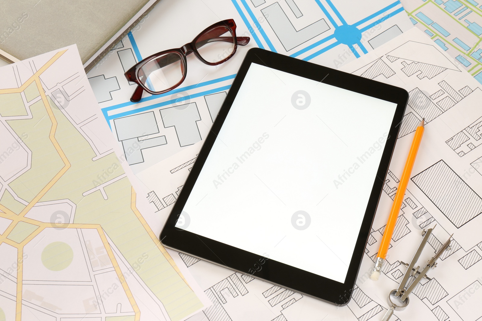 Photo of Office stationery, eyeglasses and tablet on cadastral maps of territory with buildings