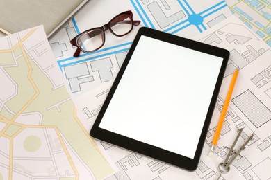 Photo of Office stationery, eyeglasses and tablet on cadastral maps of territory with buildings