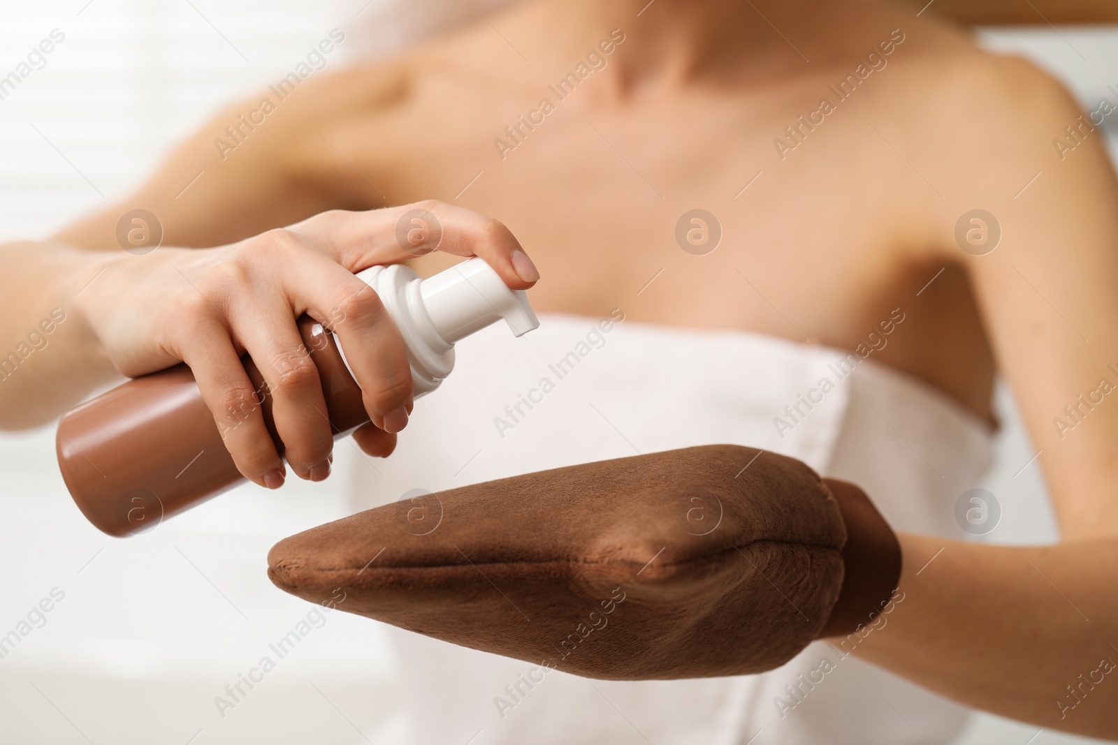 Photo of Self-tanning. Woman applying cosmetic product onto tanning mitt indoors, closeup