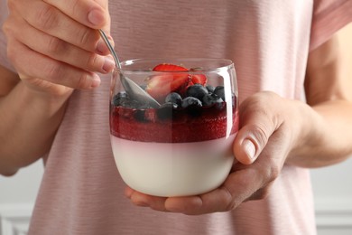 Woman eating delicious panna cotta with berries, closeup