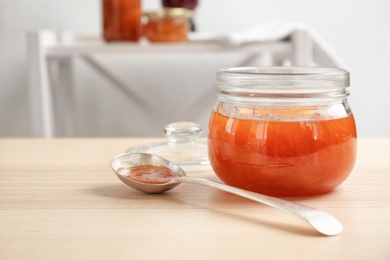 Photo of Jar and spoon with sweet jam on wooden table