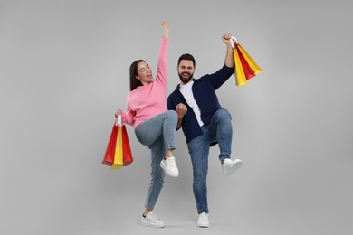 Photo of Happy couple with shopping bags having fun on grey background