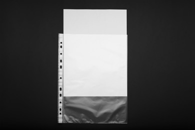 Photo of Punched pocket with paper sheet on black background, top view. Space for text