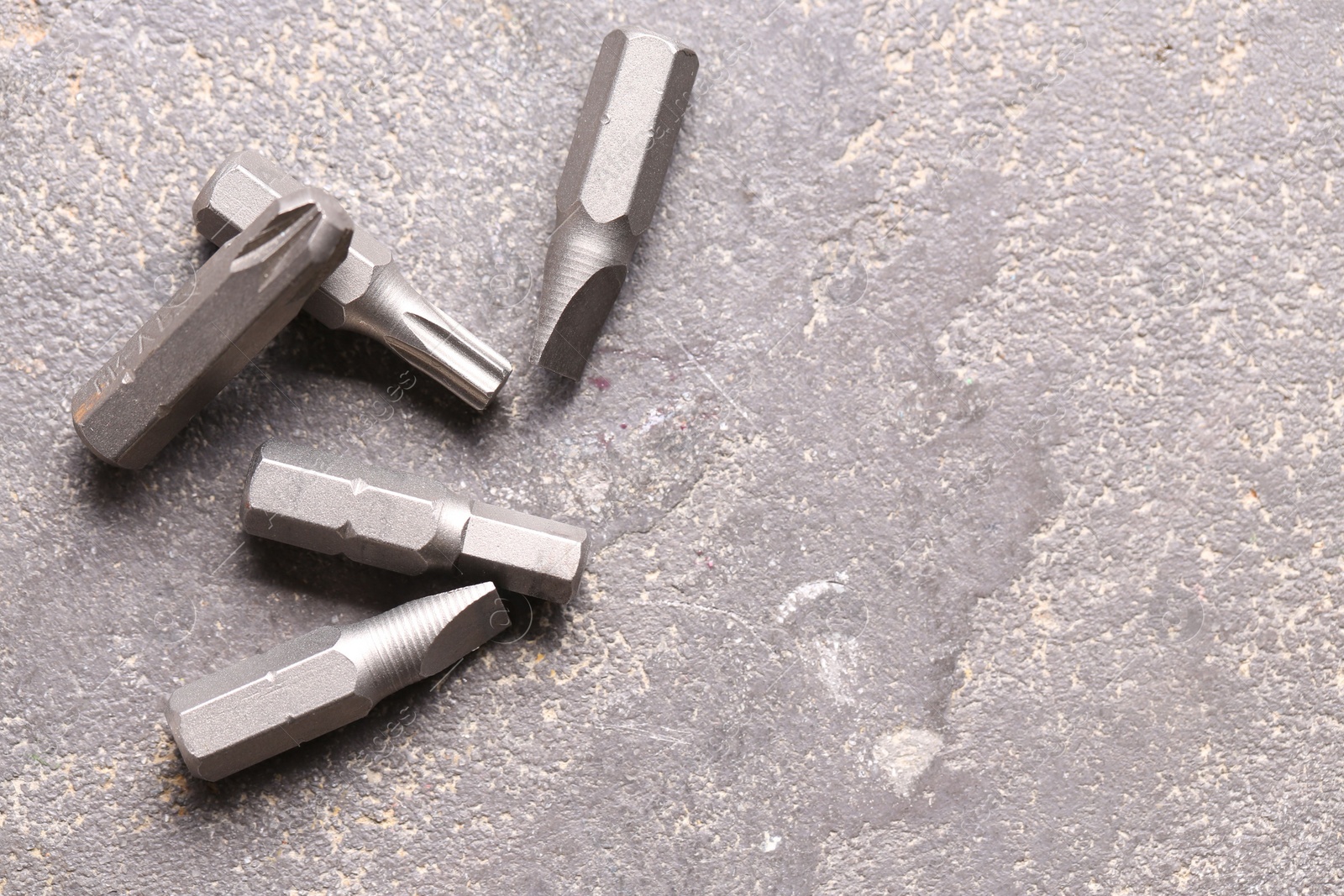 Photo of Different screwdriver bits on grey table, top view. Space for text