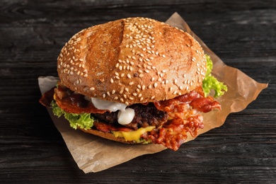 Tasty burger with bacon on wooden table
