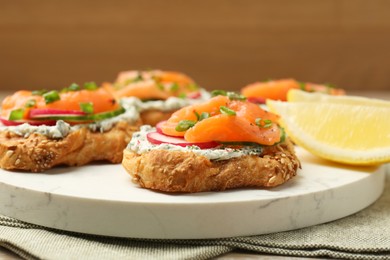 Tasty canapes with salmon, cucumber, radish and cream cheese on table, closeup