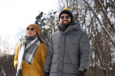 Beautiful happy couple walking in snowy park on winter day