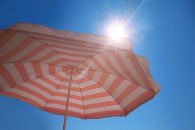 Photo of Red and white striped beach umbrella against blue sky on sunny day