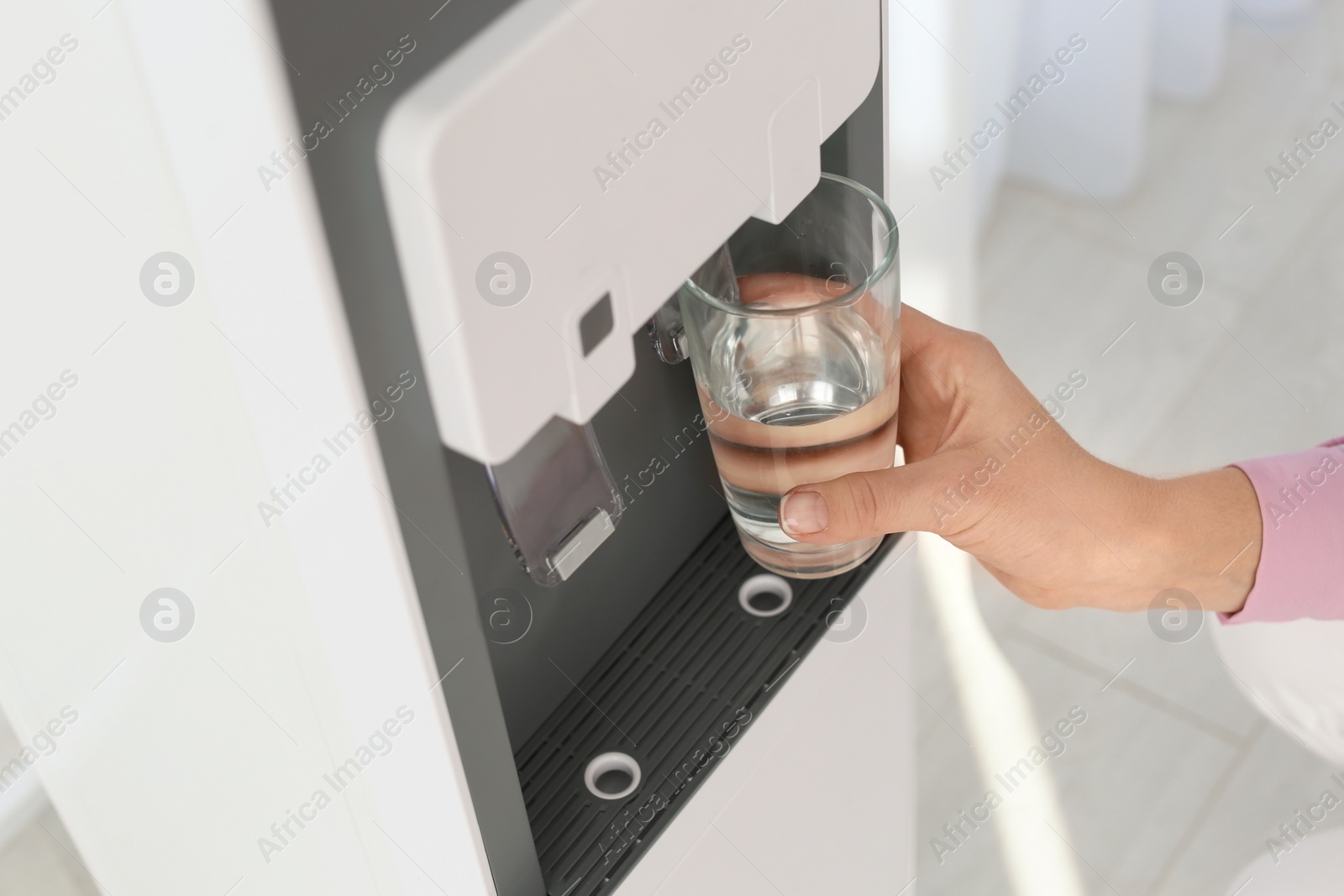 Photo of Woman filling glass from water cooler indoors, closeup