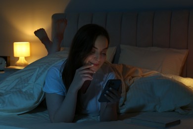 Woman using smartphone in bed at night. Internet addiction