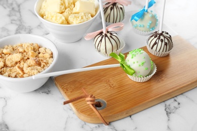 Tasty colorful cake pops on white marble table