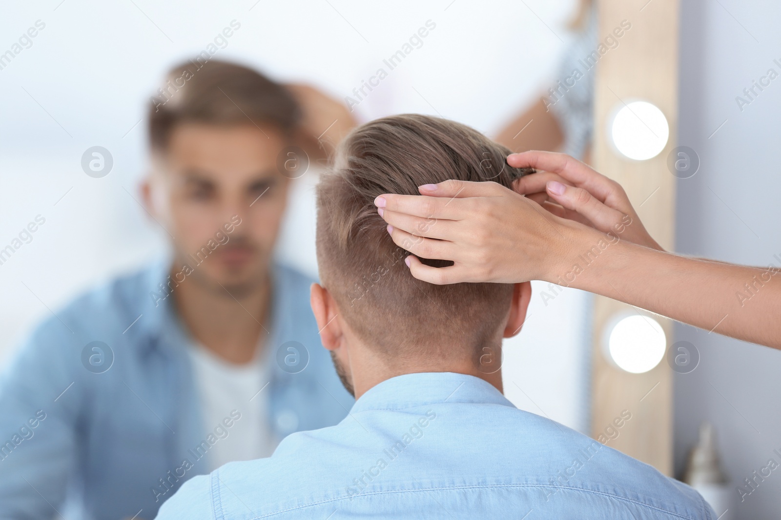 Photo of Professional hairdresser working with young man in barbershop. Trendy hair color